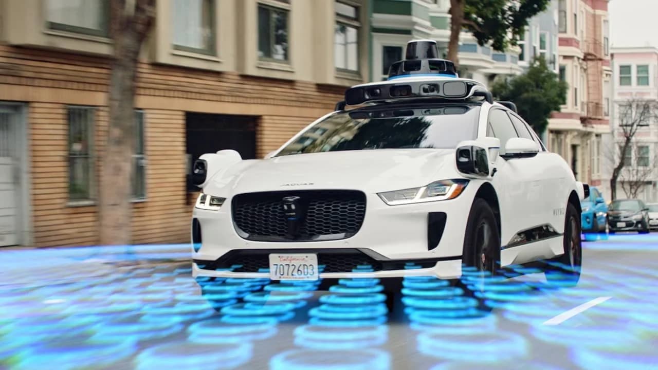 Tesla robotaxi scale fleet on city streets contrasted with a sensor-heavy Waymo vehicle