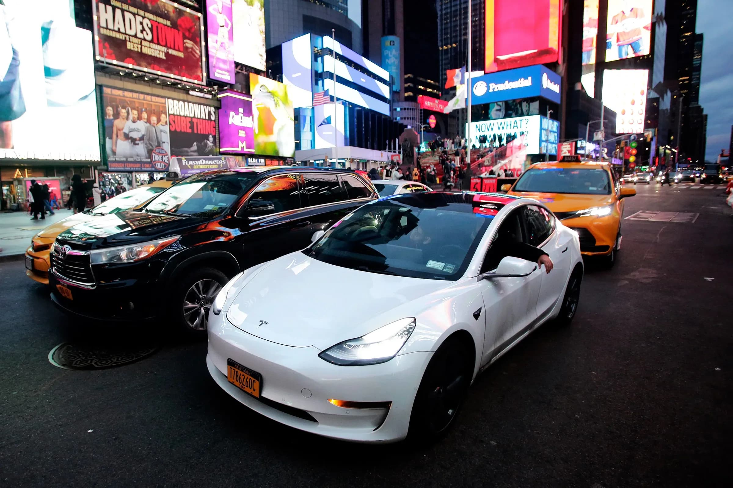 Tesla running FSD Version 14 navigating busy Manhattan traffic with pedestrians and yellow cabs